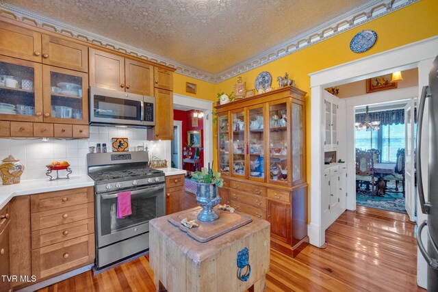 201 W Wanola Ave, Kingsport, TN 37660 - kitchen featuring appliances with stainless steel finishes, light countertops, light wood finished floors, backsplash, and a chandelier