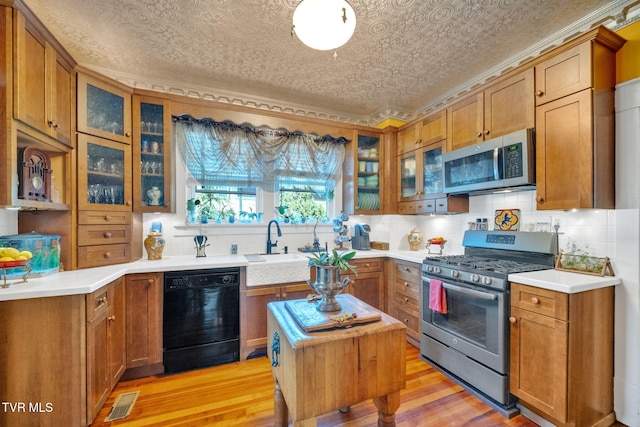 201 W Wanola Ave, Kingsport, TN 37660 - kitchen with appliances with stainless steel finishes, light wood finished floors, brown cabinets, an ornate ceiling, and crown molding
