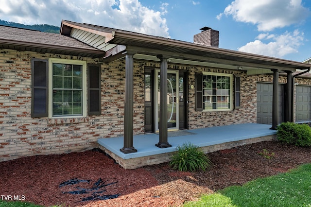 157 Spring St, Hampton, TN 37658 - entrance to property featuring covered porch, a chimney, brick siding, and a garage
