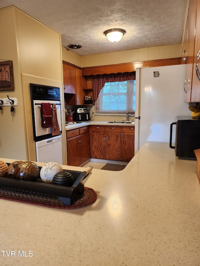 2020 Oakland St, Kingsport, TN 37660 - kitchen featuring white appliances, brown cabinetry, light countertops, and a textured ceiling