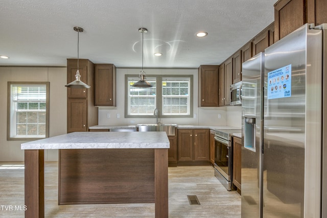 8492 Reedy Creek Rd, Bristol, VA 24202 - kitchen featuring stainless steel appliances, light countertops, light wood-type flooring, a kitchen island, and decorative light fixtures