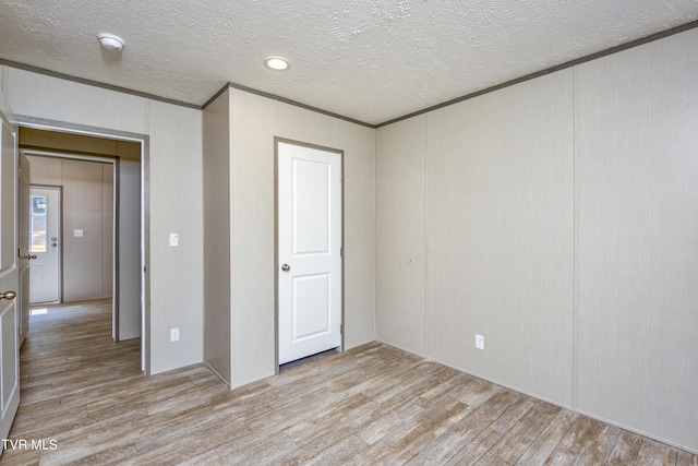 8492 Reedy Creek Rd, Bristol, VA 24202 - unfurnished bedroom featuring light wood-type flooring, crown molding, a textured ceiling, and a decorative wall