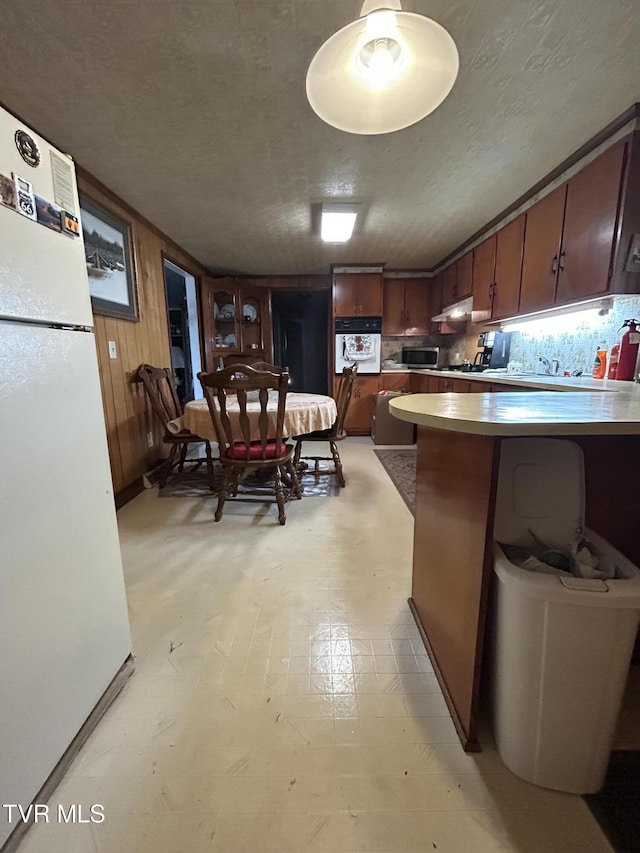 406 NE Mason Ave, Wise, VA 24293 - kitchen with white appliances, a textured ceiling, under cabinet range hood, light countertops, and a peninsula