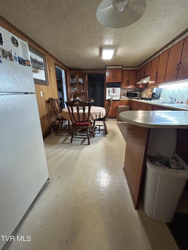 406 NE Mason Ave, Wise, VA 24293 - kitchen featuring freestanding refrigerator, brown cabinets, stainless steel microwave, light countertops, and wooden walls