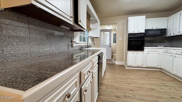 542 Sigman Hollow Rd, Bluff City, TN 37618 - kitchen with black appliances, white cabinetry, light wood-style flooring, and tasteful backsplash