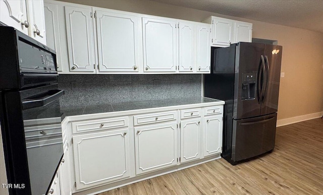 542 Sigman Hollow Rd, Bluff City, TN 37618 - kitchen featuring black appliances, white cabinets, light wood-style flooring, and backsplash