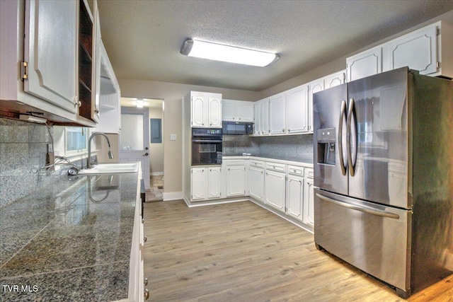542 Sigman Hollow Rd, Bluff City, TN 37618 - kitchen featuring black appliances, tile counters, light wood-type flooring, white cabinetry, and decorative backsplash