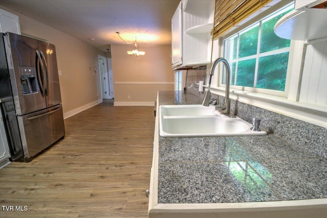 542 Sigman Hollow Rd, Bluff City, TN 37618 - kitchen with stainless steel fridge, white cabinetry, a chandelier, wood finished floors, and backsplash