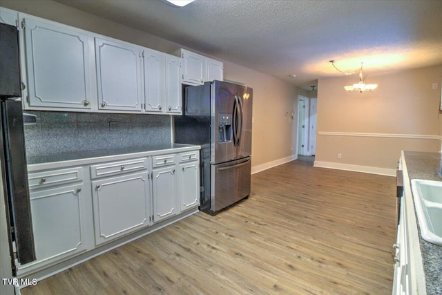 542 Sigman Hollow Rd, Bluff City, TN 37618 - kitchen with stainless steel fridge with ice dispenser, decorative backsplash, light wood-style flooring, a chandelier, and a textured ceiling