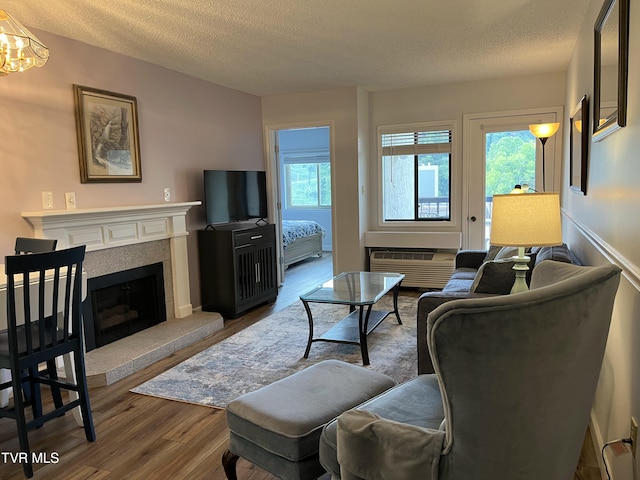 102 Baskins Creek Byp Unit 209, Gatlinburg, TN 37738 - living room featuring wood finished floors, a textured ceiling, a wall mounted air conditioner, a tile fireplace, and a chandelier