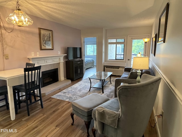 102 Baskins Creek Byp Unit 209, Gatlinburg, TN 37738 - living area with wood finished floors, a textured ceiling, a fireplace with raised hearth, a chandelier, and a wall mounted air conditioner