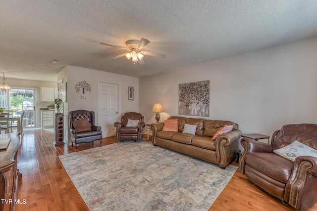 147 Rainbow Cir Unit 147, Bristol, VA 24202 - living room with a textured ceiling, light wood-style flooring, a ceiling fan, and a chandelier
