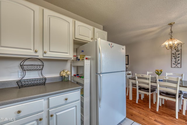 147 Rainbow Cir Unit 147, Bristol, VA 24202 - kitchen with freestanding refrigerator, dark countertops, hanging light fixtures, white cabinets, and a textured ceiling
