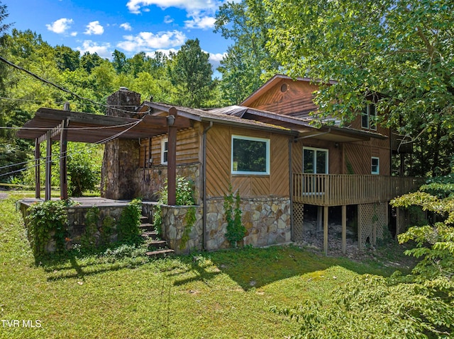 285 Vanover Ln, Jacksboro, TN 37757 - view of property exterior with stone siding, a yard, a chimney, a deck, and a metal roof