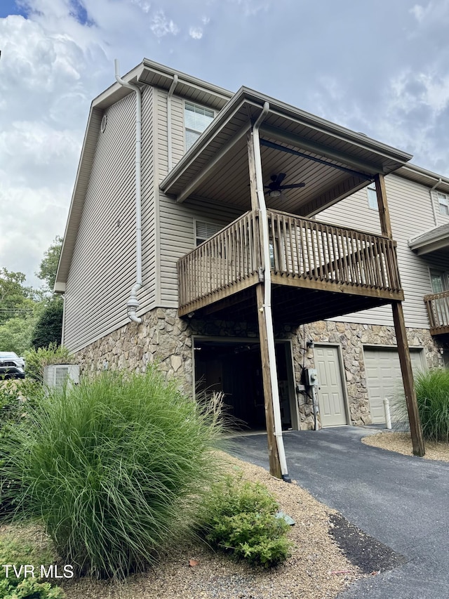 220 Cedar Creek Rd Unit 1, Johnson City, TN 37615 - view of side of home with stone siding, asphalt driveway, a garage, a ceiling fan, and a wooden deck