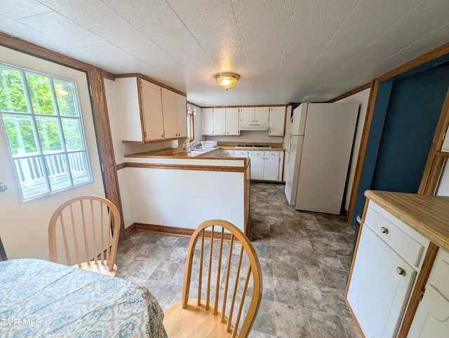 2005 Dc Caney Ridge Rd, Clintwood, VA 24228 - kitchen featuring freestanding refrigerator, gas stovetop, a peninsula, white cabinetry, and under cabinet range hood