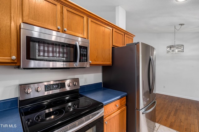216 Mockingbird Pl, Jonesborough, TN 37659 - kitchen featuring appliances with stainless steel finishes, brown cabinetry, dark countertops, dark wood-type flooring, and pendant lighting