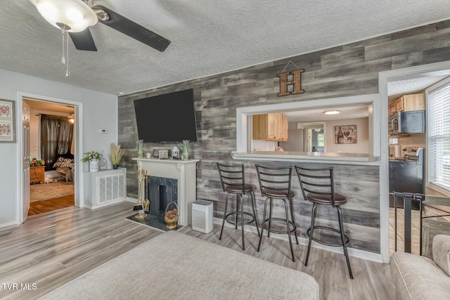 218 Kirkwood St, Glade Spring, VA 24340 - bar featuring stainless steel microwave, a textured ceiling, light wood finished floors, ceiling fan, and wood walls
