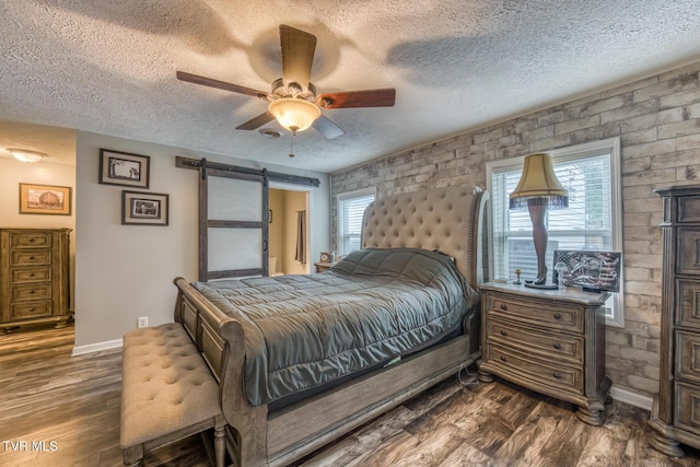 218 Kirkwood St, Glade Spring, VA 24340 - bedroom with dark wood-style flooring, a textured ceiling, a barn door, and ceiling fan