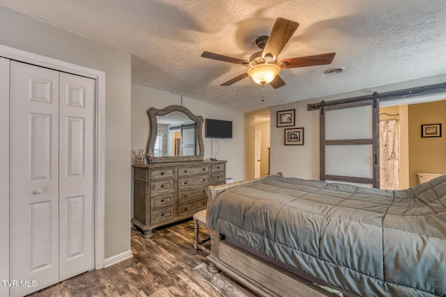 218 Kirkwood St, Glade Spring, VA 24340 - bedroom featuring dark wood finished floors, a textured ceiling, a barn door, and ceiling fan