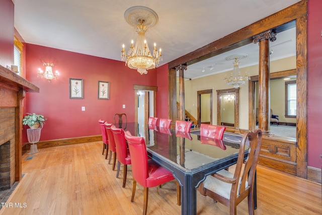 522 Alabama St, Bristol, TN 37620 - dining area with a chandelier, wood finished floors, a fireplace, crown molding, and decorative columns
