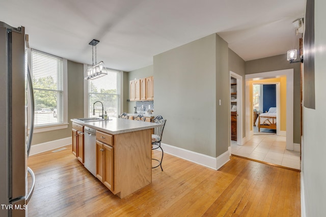 522 Alabama St, Bristol, TN 37620 - kitchen with freestanding refrigerator, white dishwasher, light wood-style flooring, light brown cabinetry, and a center island with sink
