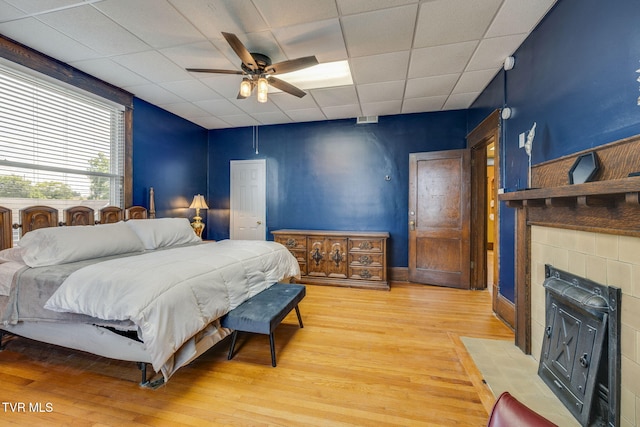 522 Alabama St, Bristol, TN 37620 - bedroom with light wood-style flooring, a tiled fireplace, a paneled ceiling, and a ceiling fan