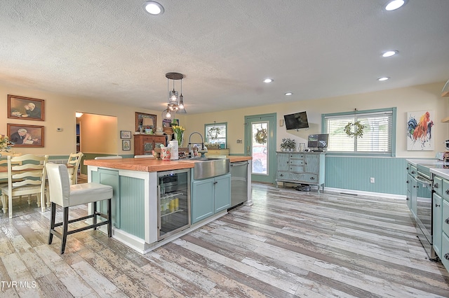 1108 Glen St, Bristol, TN 37620 - kitchen featuring butcher block countertops, stainless steel dishwasher, a textured ceiling, light wood-style flooring, and a center island with sink