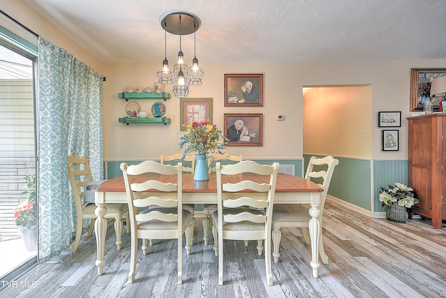 1108 Glen St, Bristol, TN 37620 - dining area featuring wood finished floors, a wainscoted wall, a chandelier, and a textured ceiling