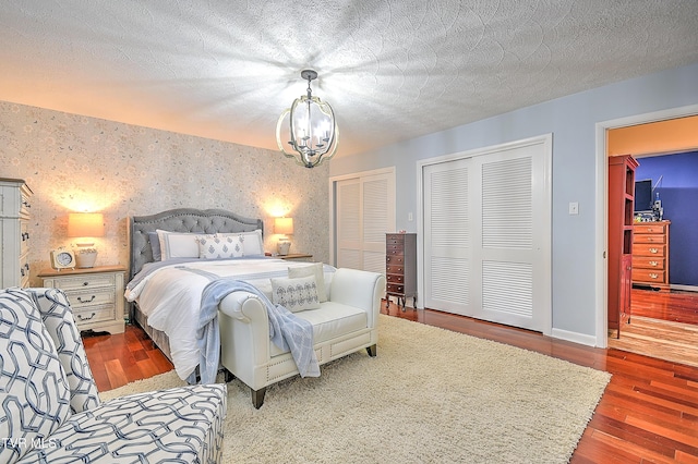 1108 Glen St, Bristol, TN 37620 - bedroom with multiple closets, a chandelier, wood finished floors, an accent wall, and a textured ceiling