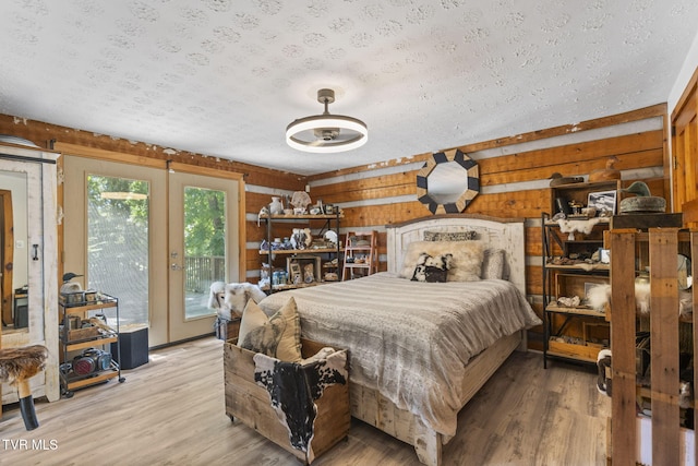 2169 Ranch Rd, Dandridge, TN 37725 - bedroom with access to outside, a textured ceiling, light wood-style floors, french doors, and wood walls