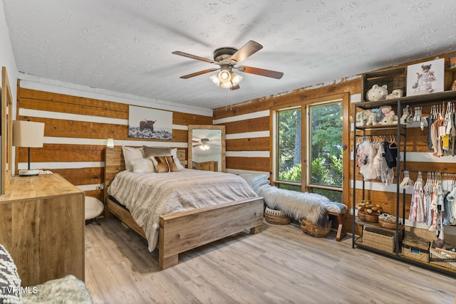 2169 Ranch Rd, Dandridge, TN 37725 - bedroom featuring a textured ceiling, wood walls, wood finished floors, and ceiling fan