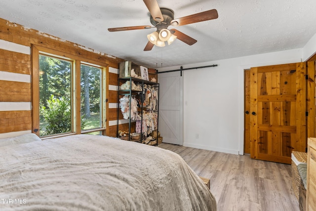 2169 Ranch Rd, Dandridge, TN 37725 - bedroom with a barn door, a textured ceiling, wood finished floors, and ceiling fan