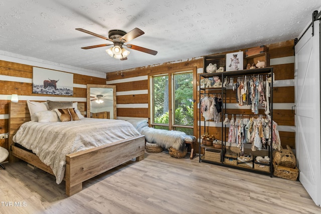 2169 Ranch Rd, Dandridge, TN 37725 - bedroom with a textured ceiling, a barn door, wood walls, wood finished floors, and a ceiling fan