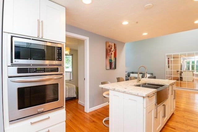 10 Grove Sq Unit 10, Randolph, MA 02368 - kitchen featuring appliances with stainless steel finishes, light wood-type flooring, a sink, recessed lighting, and white cabinetry