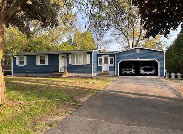 ranch-style house with driveway, entry steps, fence, a front yard, and a garage