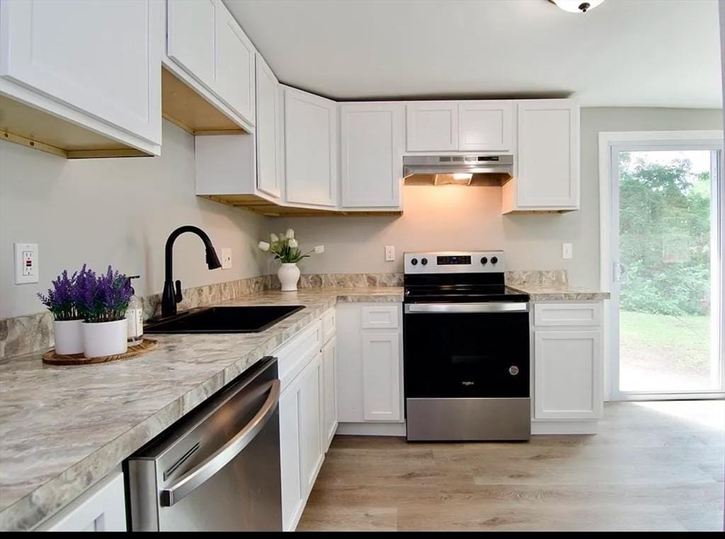 kitchen with a sink, white cabinetry, under cabinet range hood, and stainless steel appliances