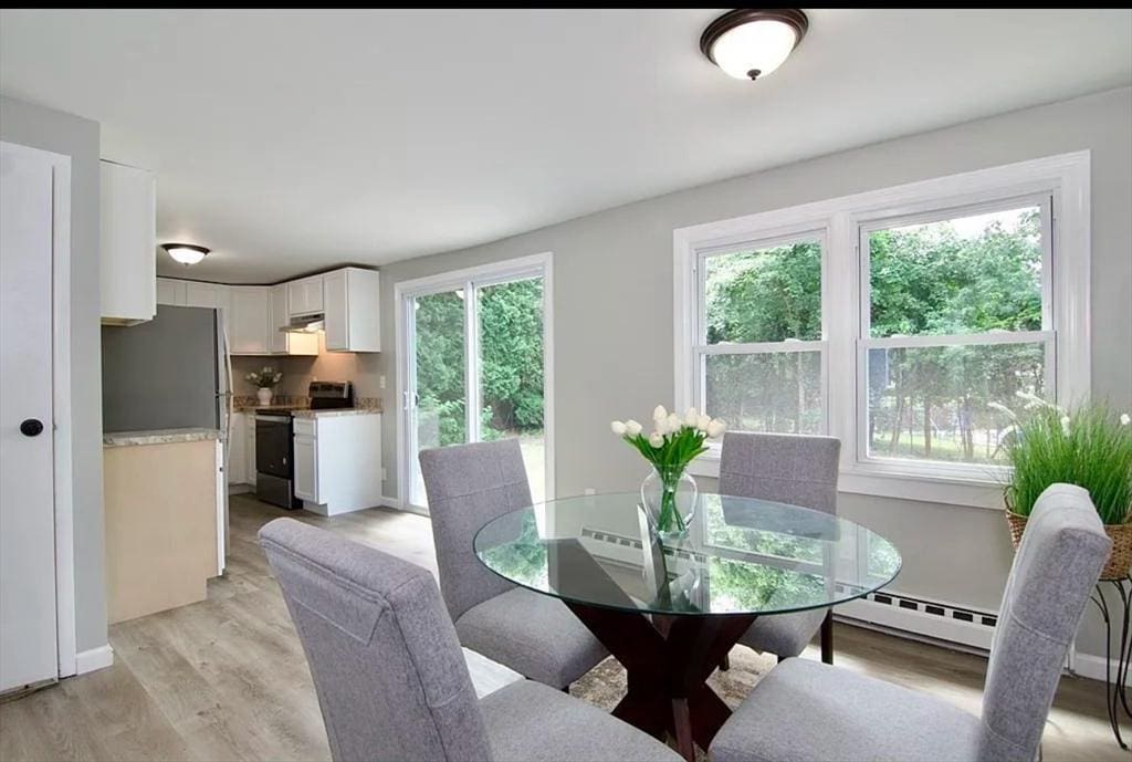 dining area with light wood-type flooring, baseboards, and a baseboard radiator