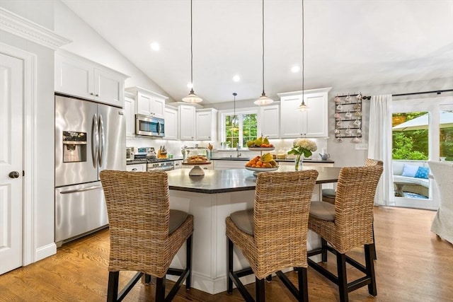 16 Lochmont St, North Attleboro, MA 02760 - kitchen with stainless steel appliances, dark countertops, lofted ceiling, wood finished floors, and a breakfast bar