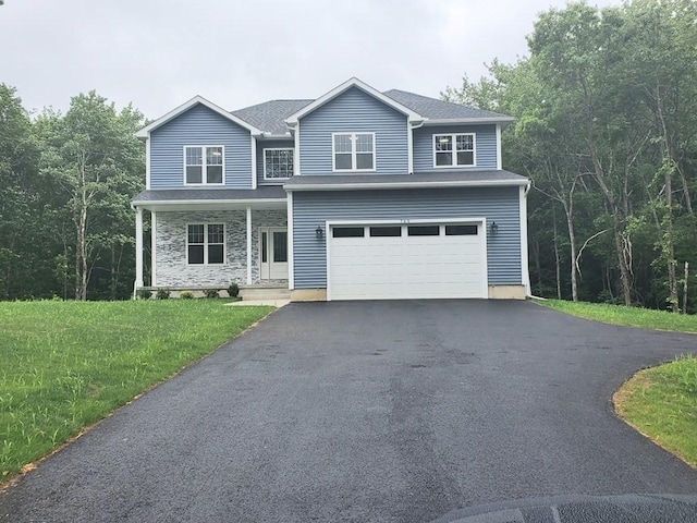 749 W St, Ludlow, MA 01056 - view of front facade featuring driveway, an attached garage, a front yard, stone siding, and covered porch