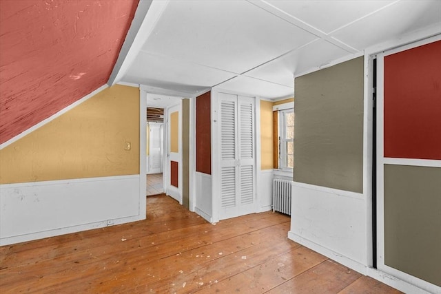 additional living space with lofted ceiling, radiator heating unit, and wood-type flooring