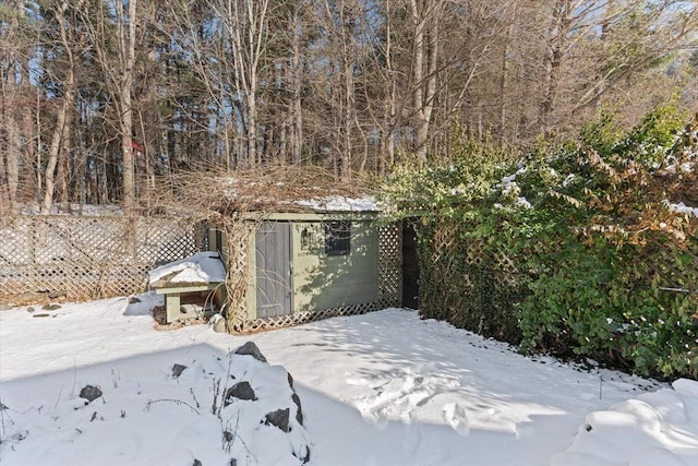 yard covered in snow with an outbuilding, fence, and a shed