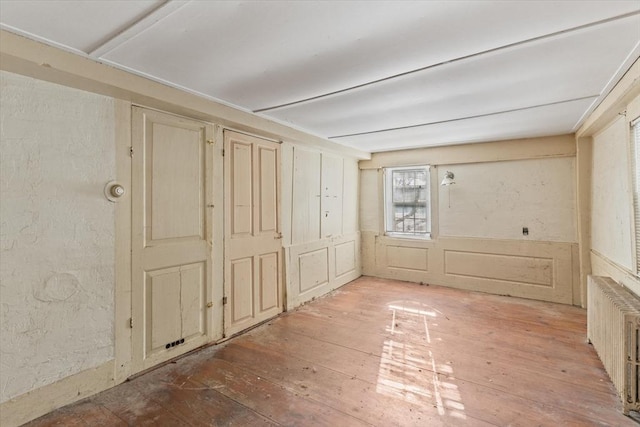 empty room featuring radiator heating unit and hardwood / wood-style floors