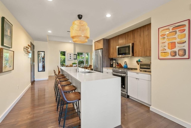 kitchen with sink, a kitchen breakfast bar, a center island with sink, white cabinets, and appliances with stainless steel finishes