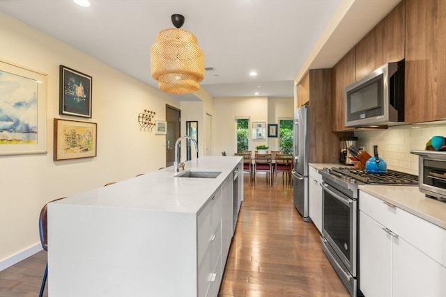 kitchen featuring appliances with stainless steel finishes, sink, a center island with sink, hardwood / wood-style flooring, and white cabinetry