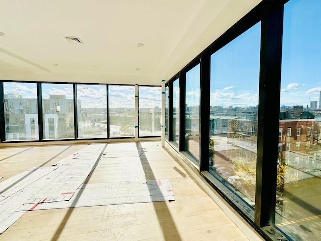 unfurnished sunroom with a view of city, visible vents, and basketball court