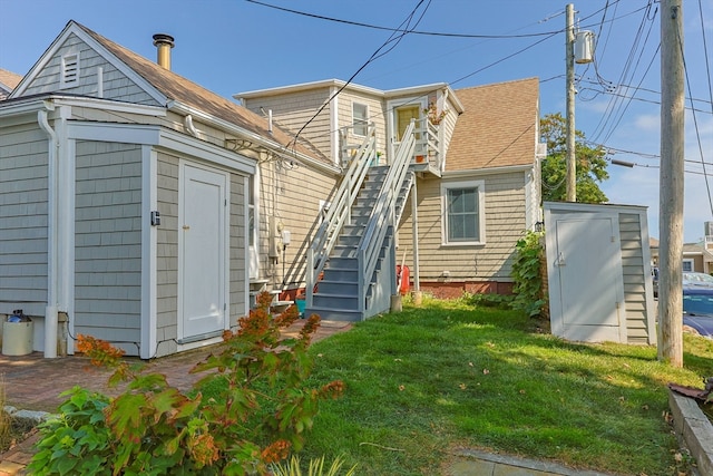 back of property featuring a shed and a lawn