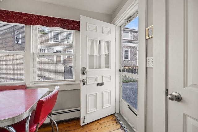 doorway to outside with a baseboard heating unit and hardwood / wood-style floors