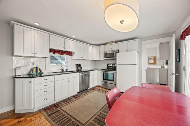 kitchen with white cabinets, sink, tasteful backsplash, wood-type flooring, and stainless steel appliances