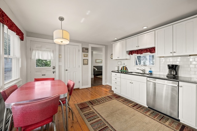 kitchen featuring hanging light fixtures, white cabinets, dishwasher, hardwood / wood-style flooring, and sink